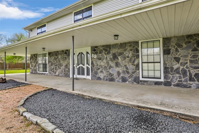 view of exterior entry with stone siding and fence