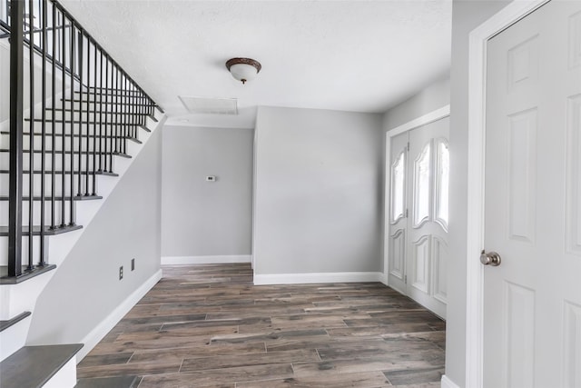 foyer entrance with dark wood finished floors, stairs, and baseboards