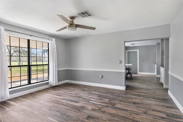 empty room featuring dark wood finished floors, visible vents, baseboards, and ceiling fan