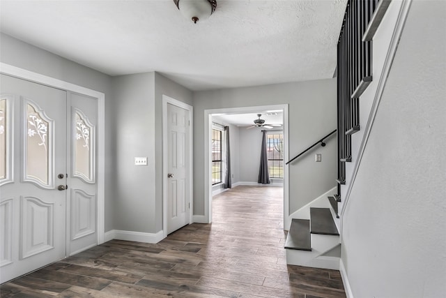 entrance foyer with baseboards, dark wood finished floors, ceiling fan, stairs, and a textured ceiling