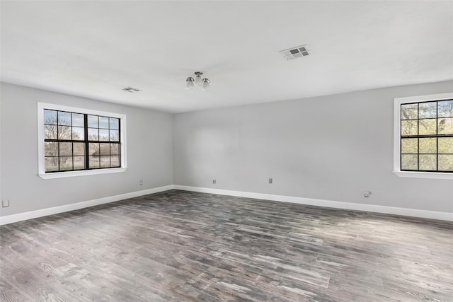 unfurnished room featuring visible vents, baseboards, and wood finished floors