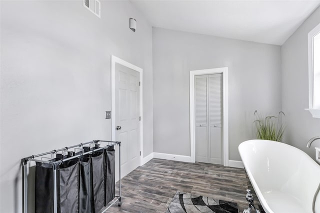 full bath featuring wood finished floors, baseboards, visible vents, lofted ceiling, and a freestanding bath