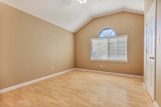 spare room featuring baseboards, light wood finished floors, a ceiling fan, and vaulted ceiling