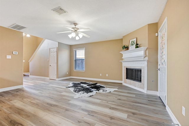 unfurnished living room featuring visible vents, light wood-style floors, ceiling fan, and a tile fireplace