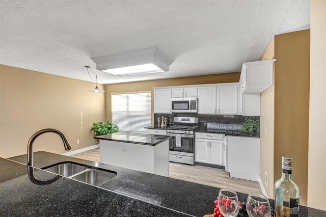 kitchen featuring a sink, stainless steel appliances, light wood-type flooring, and white cabinets