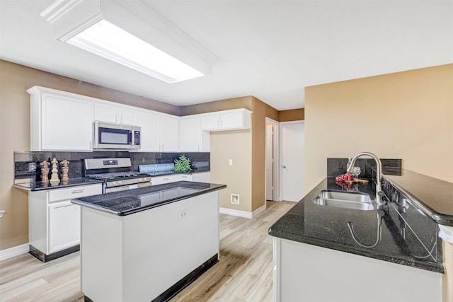 kitchen featuring a sink, stainless steel appliances, white cabinets, and dark stone counters