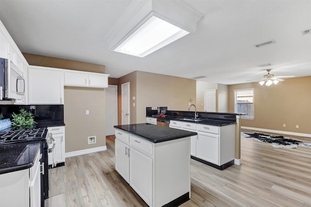 kitchen featuring a center island, light wood-style flooring, white cabinets, stainless steel appliances, and a sink