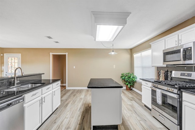 kitchen with dark countertops, light wood finished floors, stainless steel appliances, and a sink