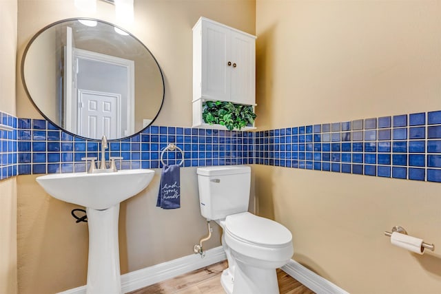 half bath featuring toilet, tile walls, and wood finished floors