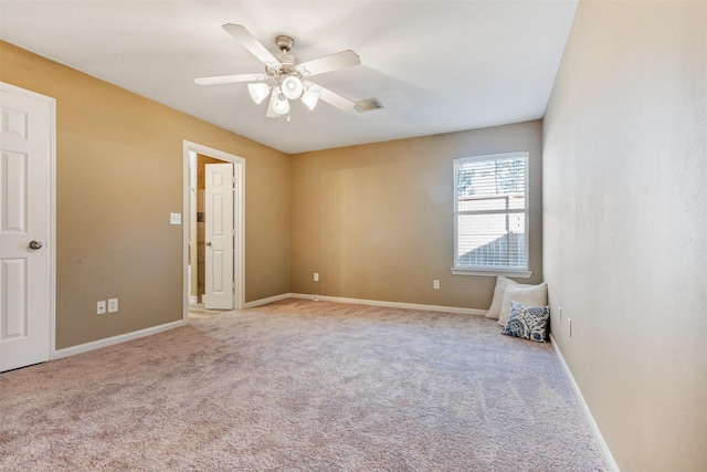 carpeted spare room with visible vents, baseboards, and a ceiling fan