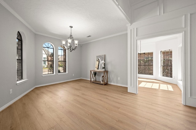 spare room with crown molding, a textured ceiling, light wood-style floors, and an inviting chandelier