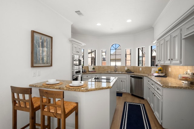 kitchen with ornamental molding, a sink, tasteful backsplash, stainless steel appliances, and a peninsula