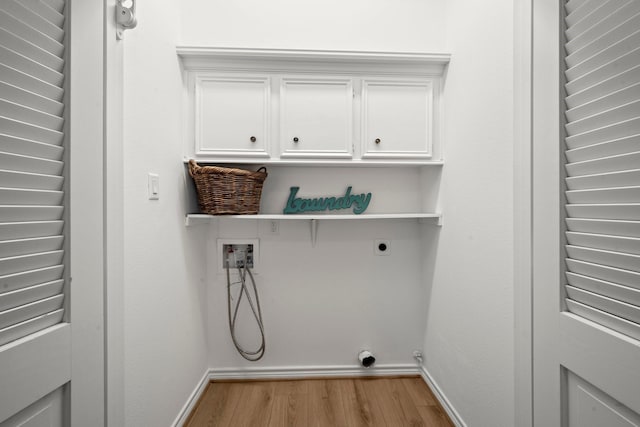 clothes washing area with baseboards, light wood-type flooring, washer hookup, cabinet space, and hookup for an electric dryer