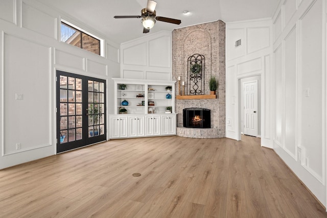 unfurnished living room featuring visible vents, high vaulted ceiling, a fireplace, french doors, and a decorative wall