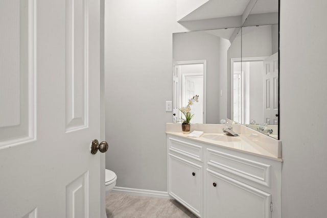 bathroom with vanity, toilet, and baseboards