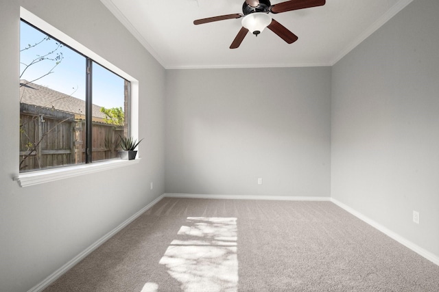 carpeted empty room featuring a ceiling fan, baseboards, and ornamental molding