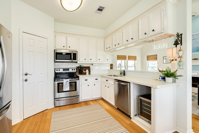 4010 Kiva Rd, Galveston, TX 77554 - kitchen featuring stainless steel appliances, a sink, light countertops, and light wood-style floors