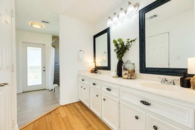 4010 Kiva Rd, Galveston, TX 77554 - bathroom with wood finished floors, double vanity, curtained shower, and baseboards