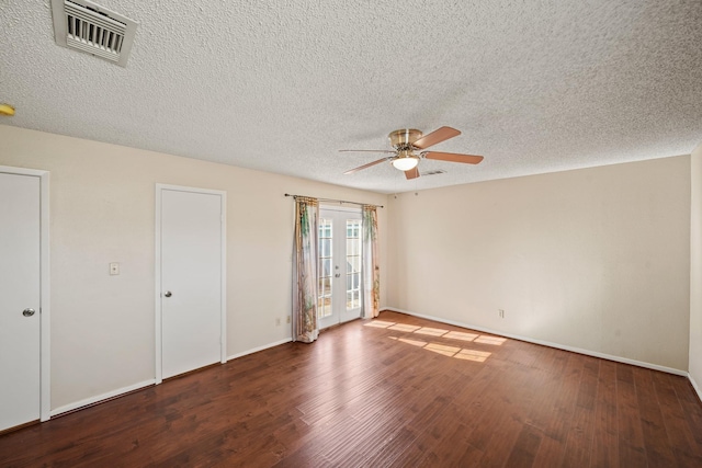 empty room with visible vents, a ceiling fan, a textured ceiling, wood finished floors, and baseboards