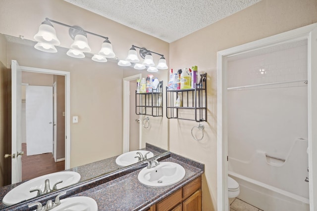 bathroom with a textured ceiling, double vanity, tile patterned flooring, and a sink