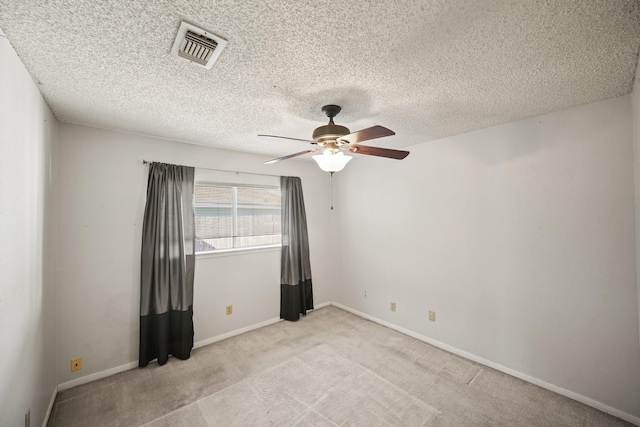 unfurnished room featuring visible vents, a ceiling fan, a textured ceiling, baseboards, and light colored carpet