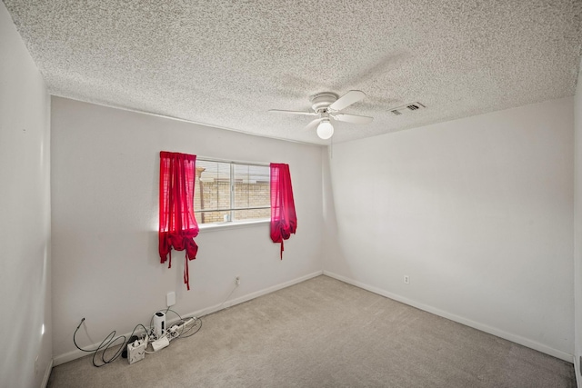 carpeted spare room with baseboards, visible vents, a textured ceiling, and a ceiling fan