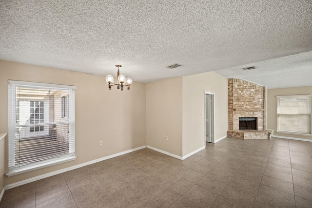 unfurnished living room featuring dark tile patterned floors, a brick fireplace, a notable chandelier, and visible vents