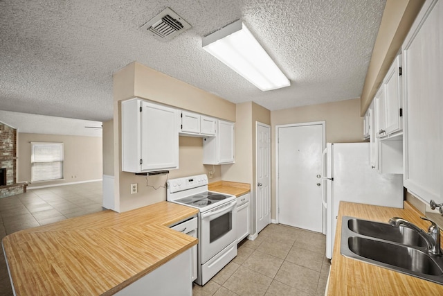 kitchen with visible vents, light tile patterned floors, white cabinets, white appliances, and a sink