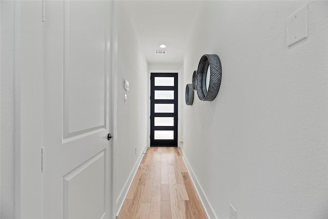 doorway featuring visible vents, baseboards, and light wood finished floors