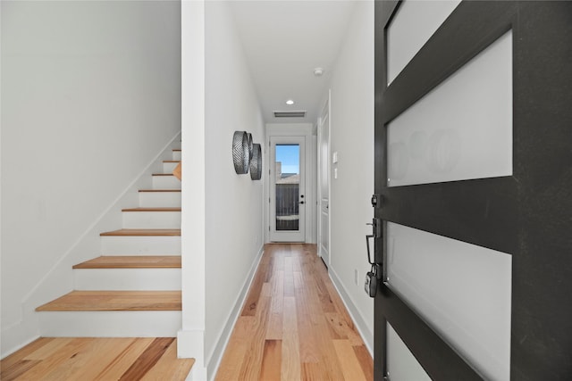 hallway featuring light wood finished floors, visible vents, stairs, and baseboards