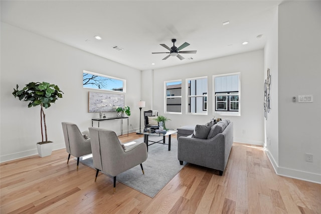 living room featuring visible vents, light wood-style flooring, baseboards, and ceiling fan