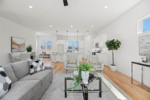 living area with recessed lighting, light wood-style flooring, and baseboards