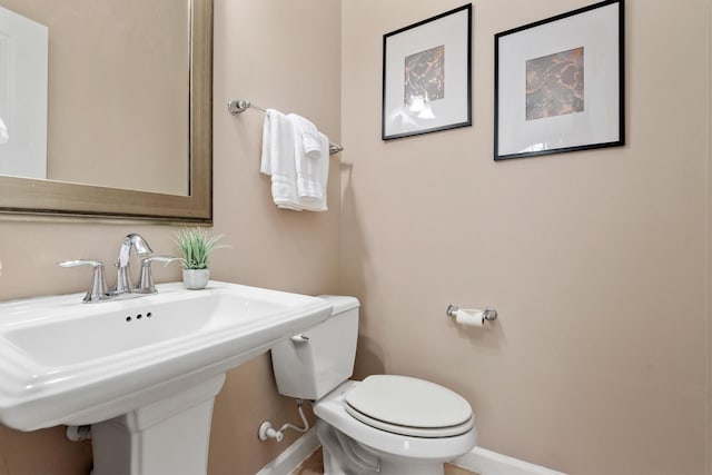 bathroom with a sink, baseboards, and toilet