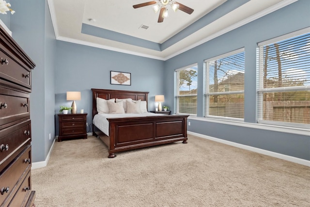 bedroom with light carpet, a raised ceiling, and baseboards