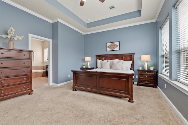 bedroom featuring visible vents, baseboards, a tray ceiling, light colored carpet, and connected bathroom