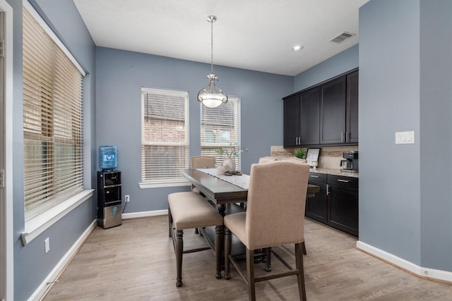 dining room featuring light wood-type flooring, visible vents, and baseboards