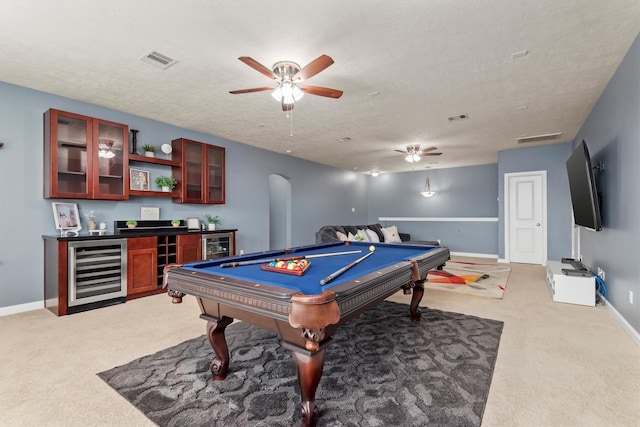 recreation room with visible vents, ceiling fan, wine cooler, light colored carpet, and a dry bar