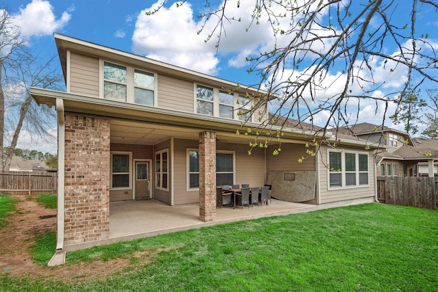 rear view of house with a patio area, a lawn, brick siding, and fence