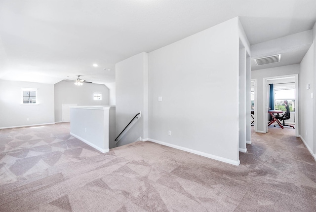 spare room with visible vents, light colored carpet, a ceiling fan, and baseboards