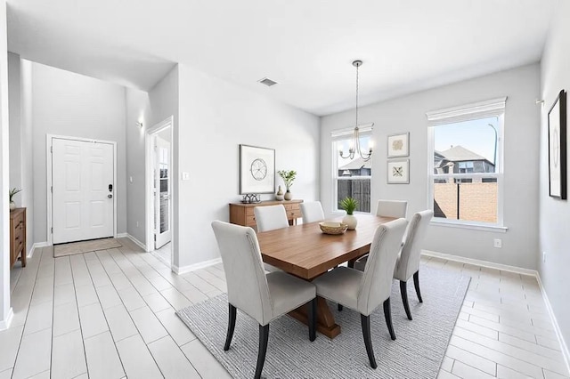 dining room featuring visible vents, baseboards, an inviting chandelier, and light wood finished floors