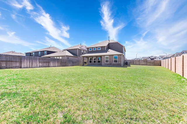 rear view of house with brick siding, a lawn, a shingled roof, and a fenced backyard