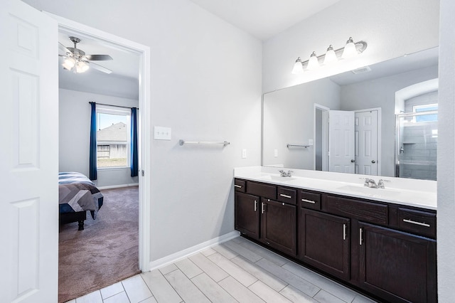 bathroom featuring baseboards, double vanity, ceiling fan, a sink, and a shower stall