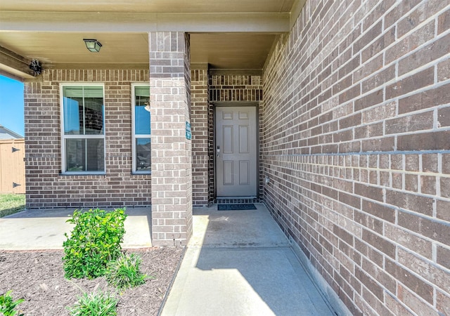 view of exterior entry featuring brick siding