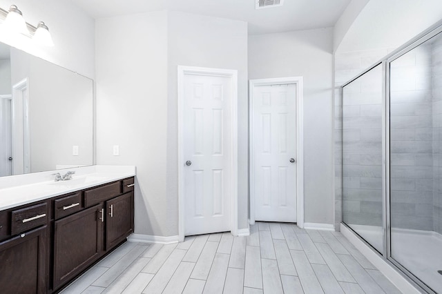 full bathroom featuring vanity, a shower stall, baseboards, and visible vents