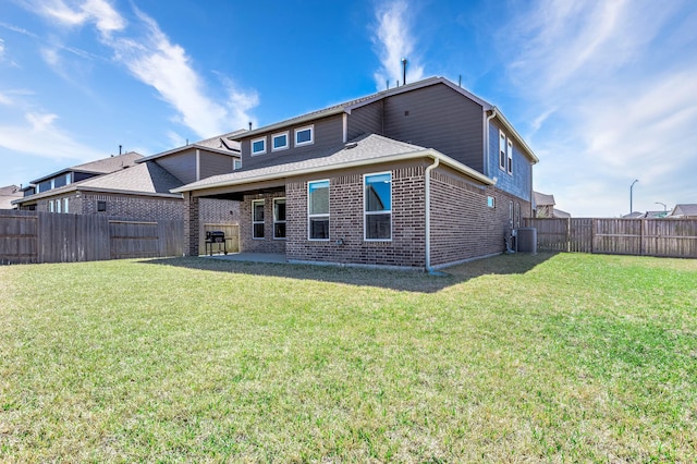 rear view of property with brick siding, a fenced backyard, a lawn, and central AC