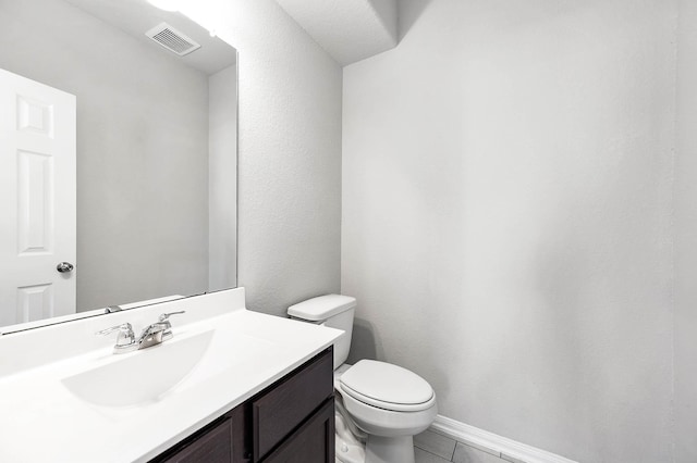 half bathroom featuring vanity, toilet, baseboards, and visible vents