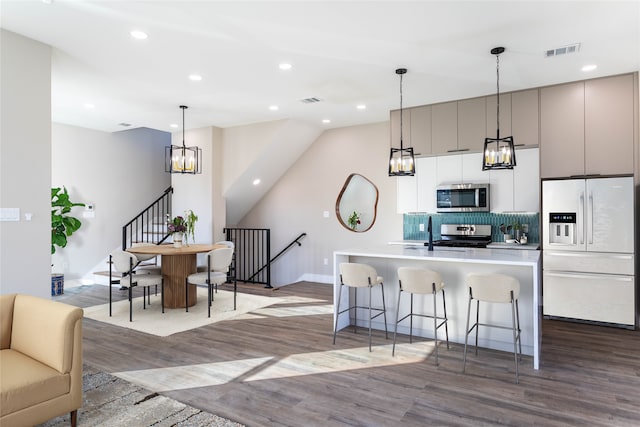 kitchen with visible vents, a chandelier, a breakfast bar area, appliances with stainless steel finishes, and wood finished floors