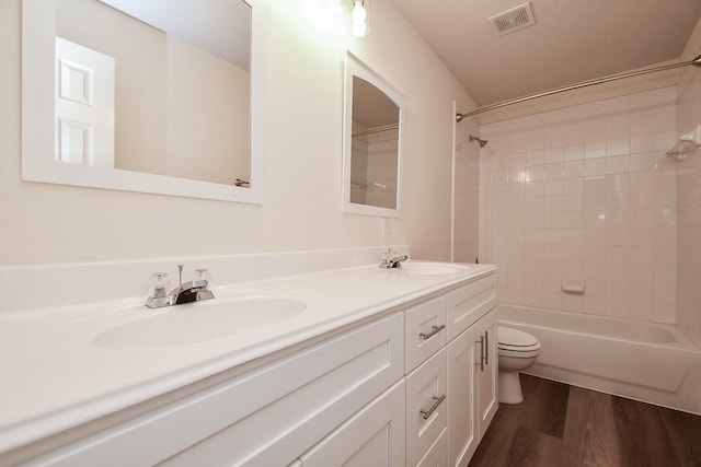 full bathroom featuring toilet, wood finished floors, visible vents, and a sink