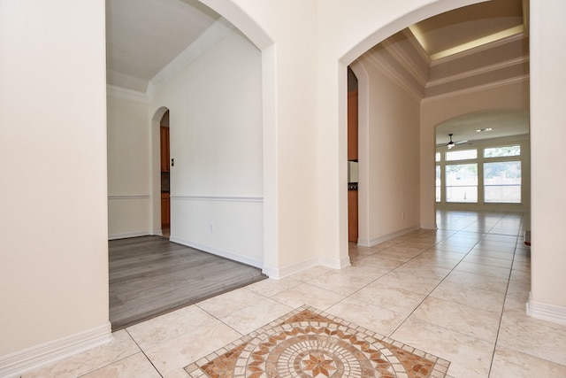 hallway with light tile patterned floors, arched walkways, baseboards, and ornamental molding