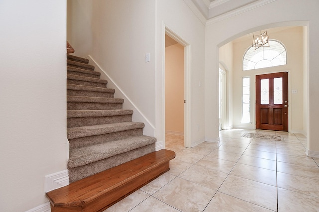 foyer entrance with stairs, light tile patterned floors, baseboards, and arched walkways